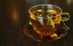 A clear glass cup of herbal tea on a wooden table.